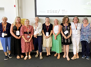 row of 9 standing women in a lecture theatre
